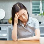 頭を抱えて悩む女性